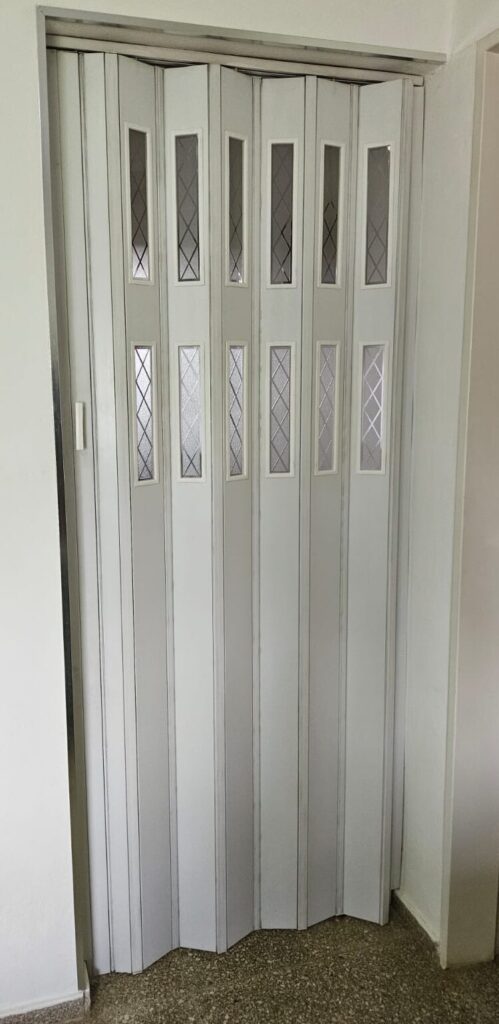 Puerta plegadiza de PVC blanca con vidrios decorativos